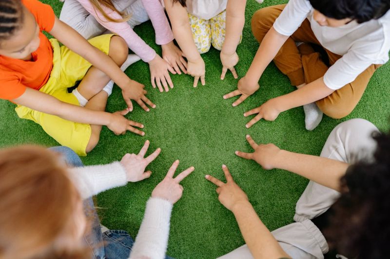 Viele Kinder sitzen im Kreis und zeigen alle in die Mitte