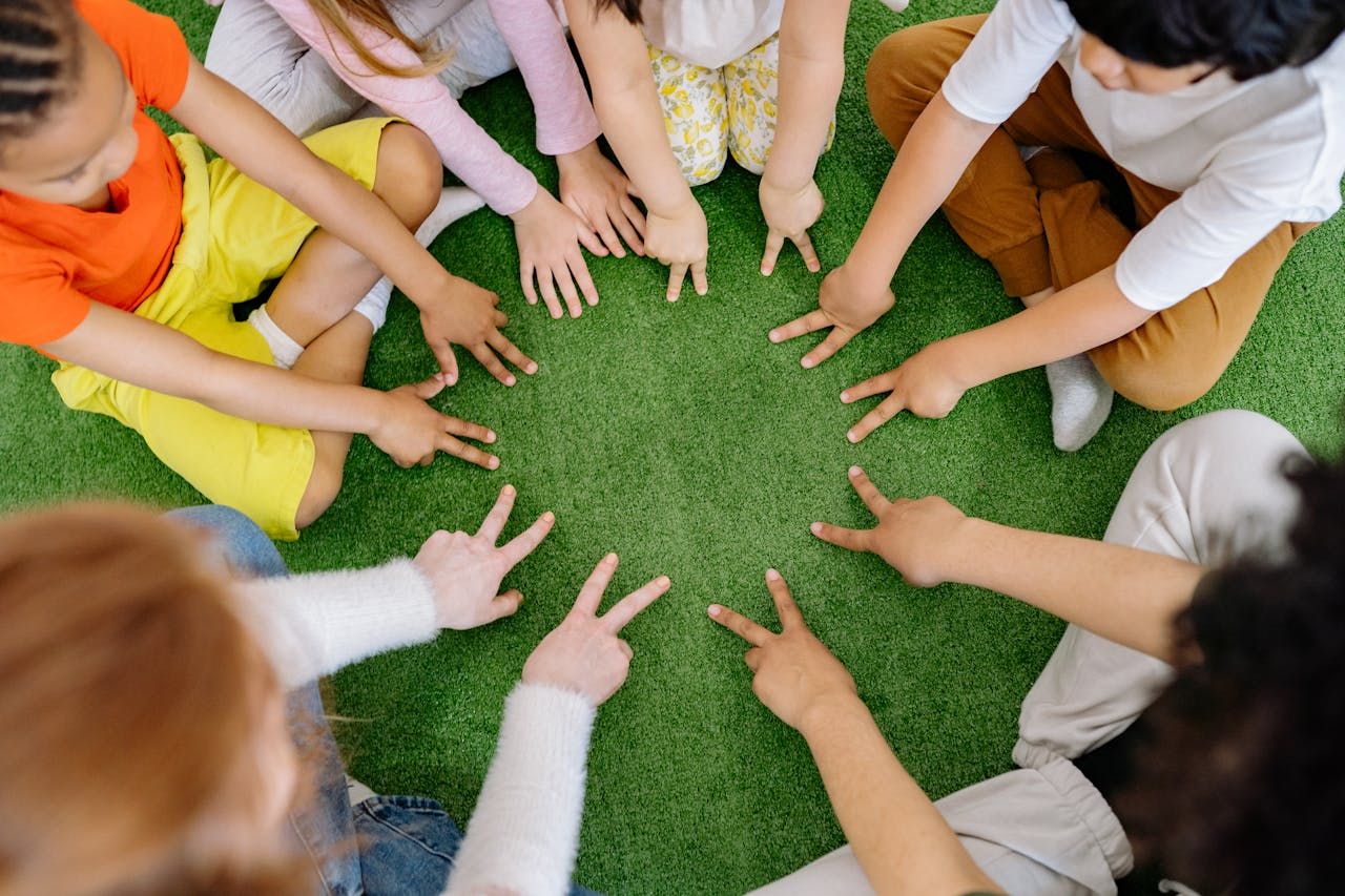 Viele Kinder sitzen im Kreis und zeigen alle in die Mitte