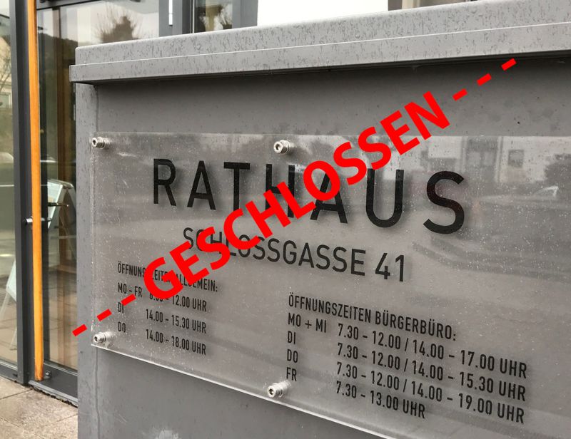 Schild mit den Öffnungszeiten vor dem Rathauseingang